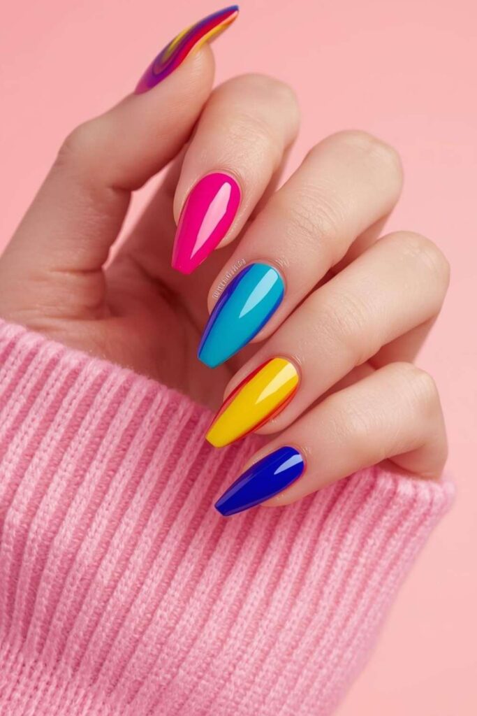 Vibrant rainbow acrylic nails featuring glossy multicolored nail polish on elegant almond-shaped nails.