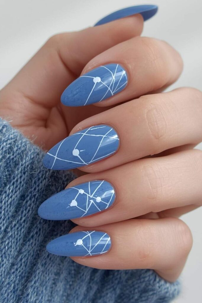 Almond-shaped washed denim blue acrylic nails featuring minimalist white abstract line art for a modern Trendy Acrylic Nails 2026 manicure.