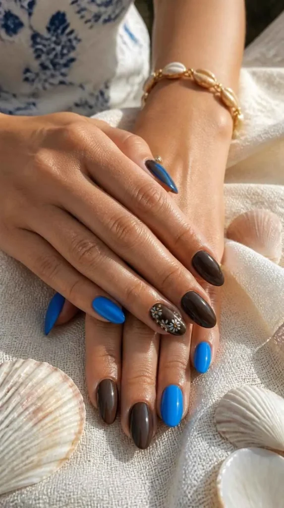 Glossy blue and chocolate brown gel nails with floral accent nail for a modern summer manicure.