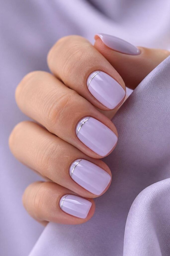 Classy short acrylic nails featuring pale lilac polish with elegant silver line nail art.