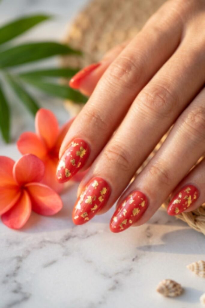 Coral red gel nails decorated with delicate gold foil accents for an elegant summer manicure