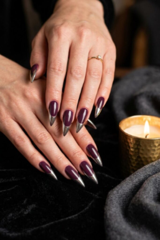 Long stiletto nails in deep plum polish finished with reflective mirror chrome French tips.