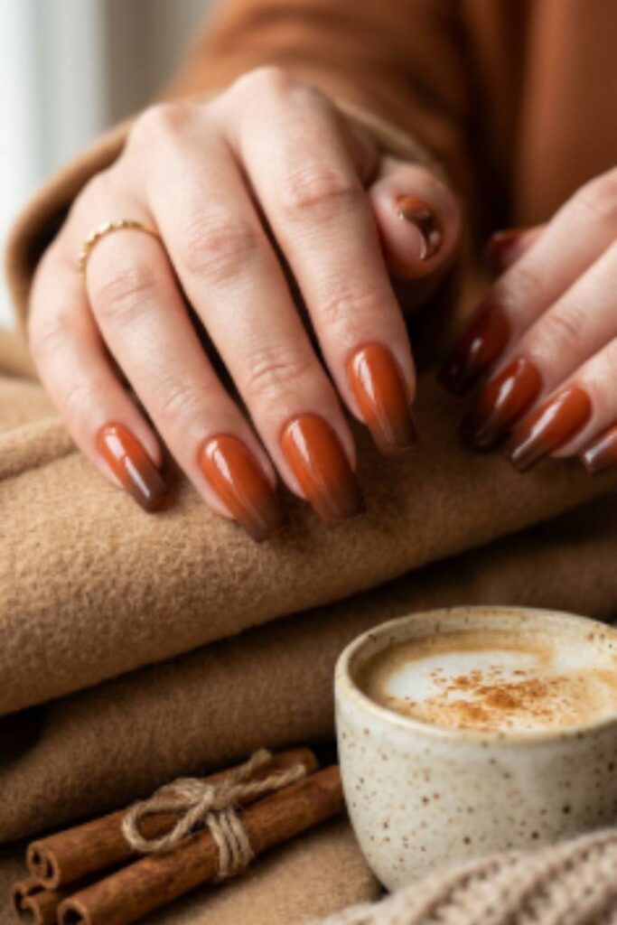 Long square nails featuring glazed rust orange polish blended into warm brown tips with a glossy finish.