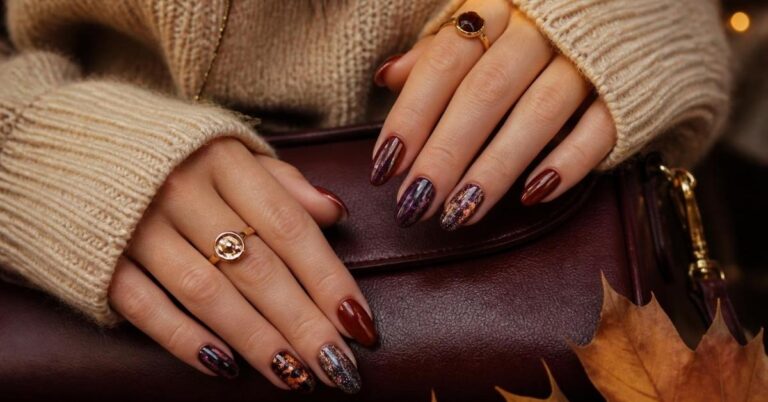 Elegant feminine hands showcasing multiple dark romantic fall nails in oxblood, smoked plum, burgundy, black cherry, antique copper, and plum noir with cozy autumn styling.