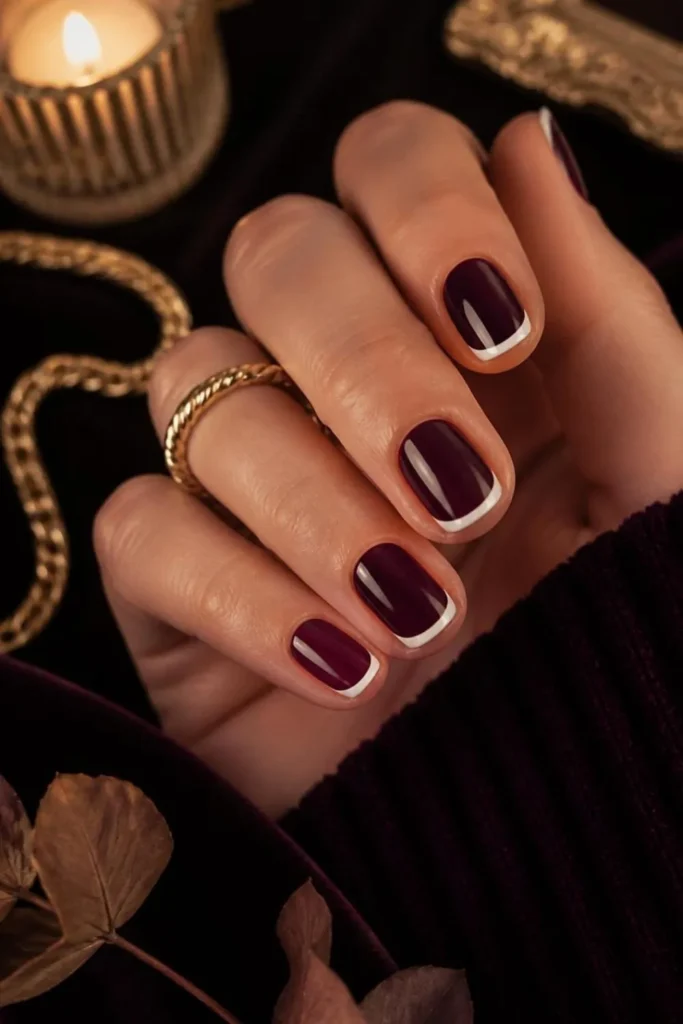 Elegant short french tip nails featuring a rich deep plum base with crisp white French tips on rounded natural nails for a sophisticated modern manicure.