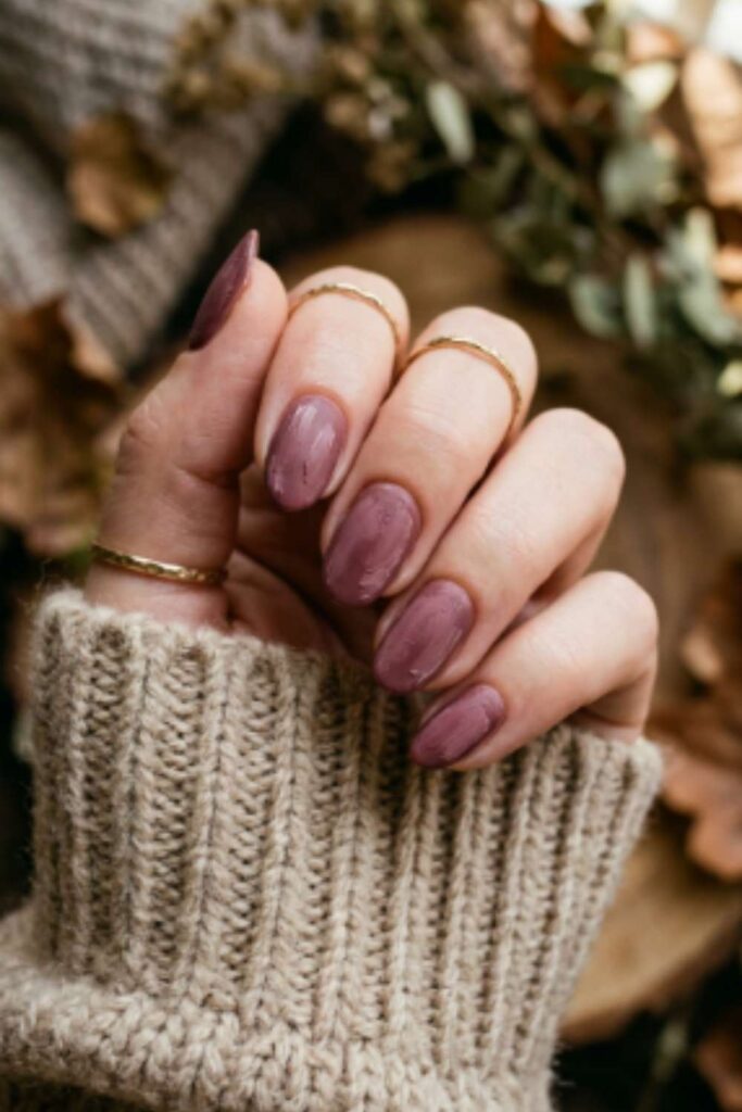 Oval nails painted in dried rose polish with artistic brushstroke texture and soft matte finish for an elegant fall manicure.