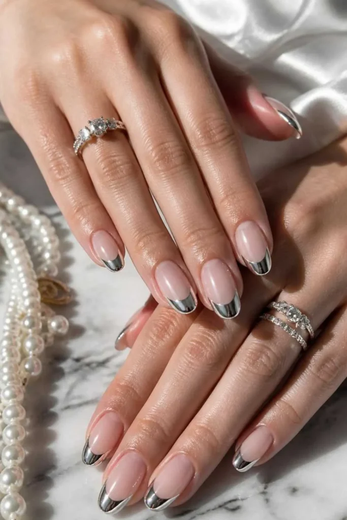 Elegant French chrome gel manicure with reflective silver tips on glossy nude nails.