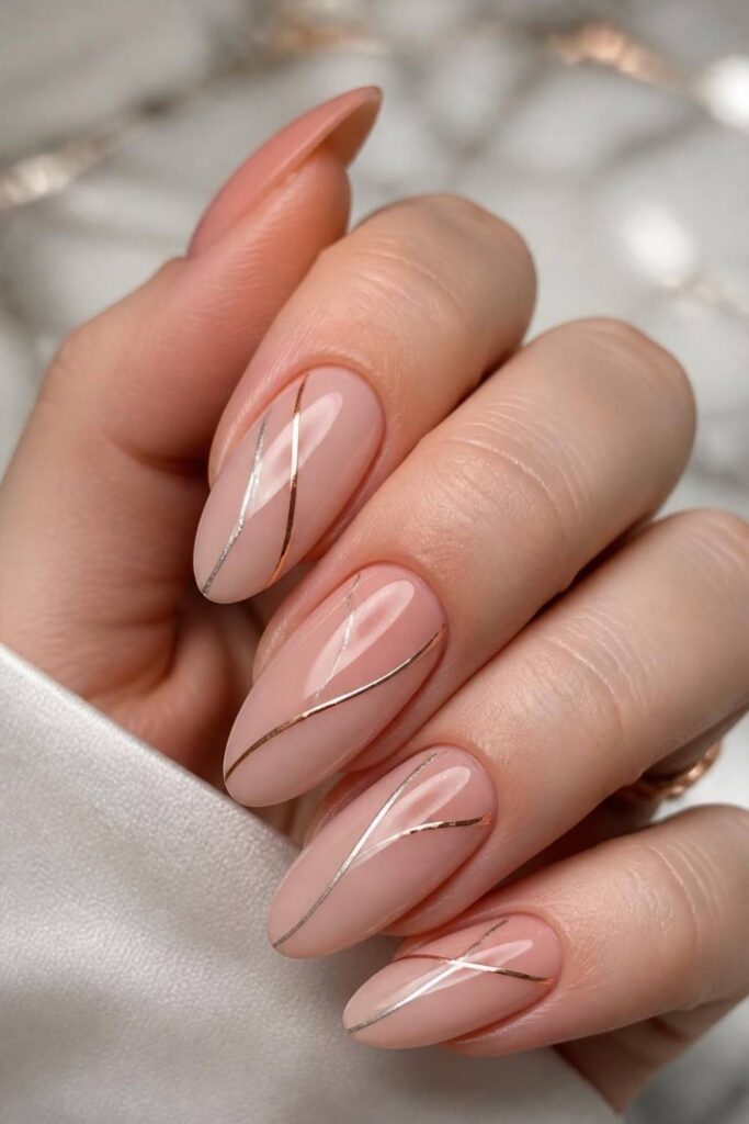 Nude pink acrylic nails featuring thin silver chrome lines on elegant almond-shaped nails.