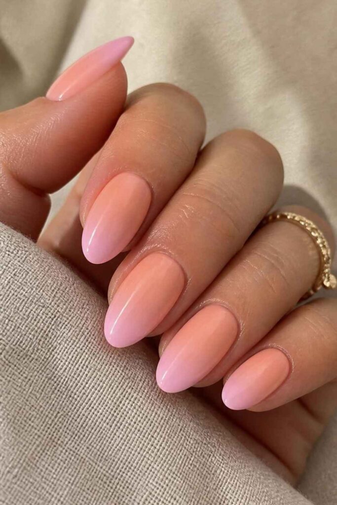 Peach-pink gradient acrylic nails with a seamless ombre fade on elegant almond-shaped nails.