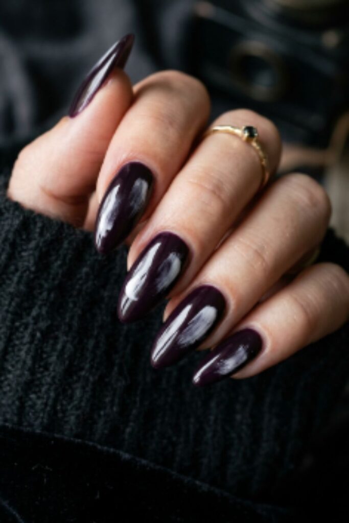 Deep plum noir nails featuring an abstract smudged white streak with glossy finish for a moody artistic fall manicure.