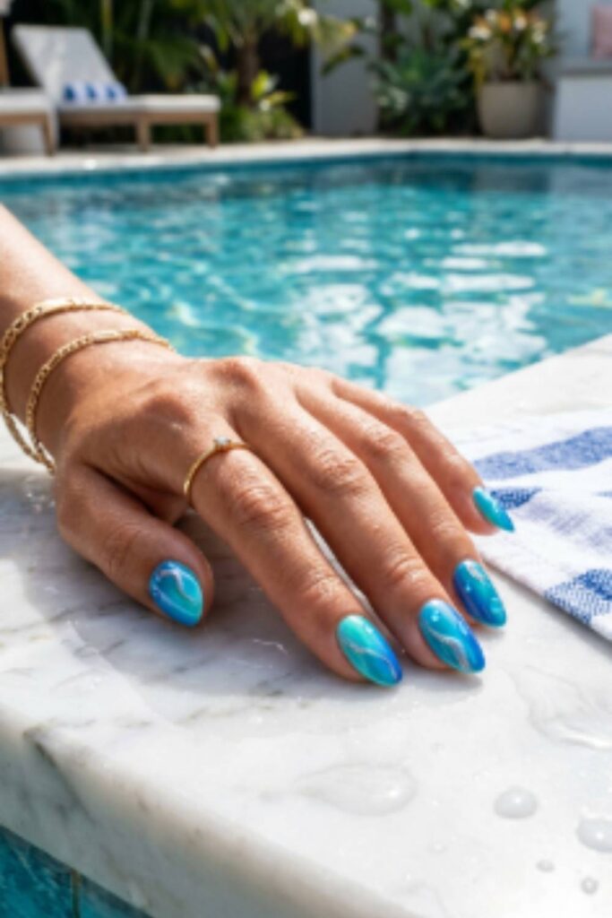 Glossy blue manicure inspired by swimming pool reflections with aqua, turquoise, and cobalt nail colors.