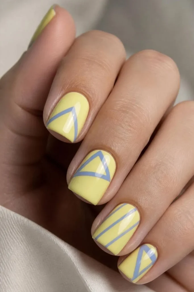 Butter yellow short nails featuring thin periwinkle geometric line art on a glossy manicure with modern minimalist styling.