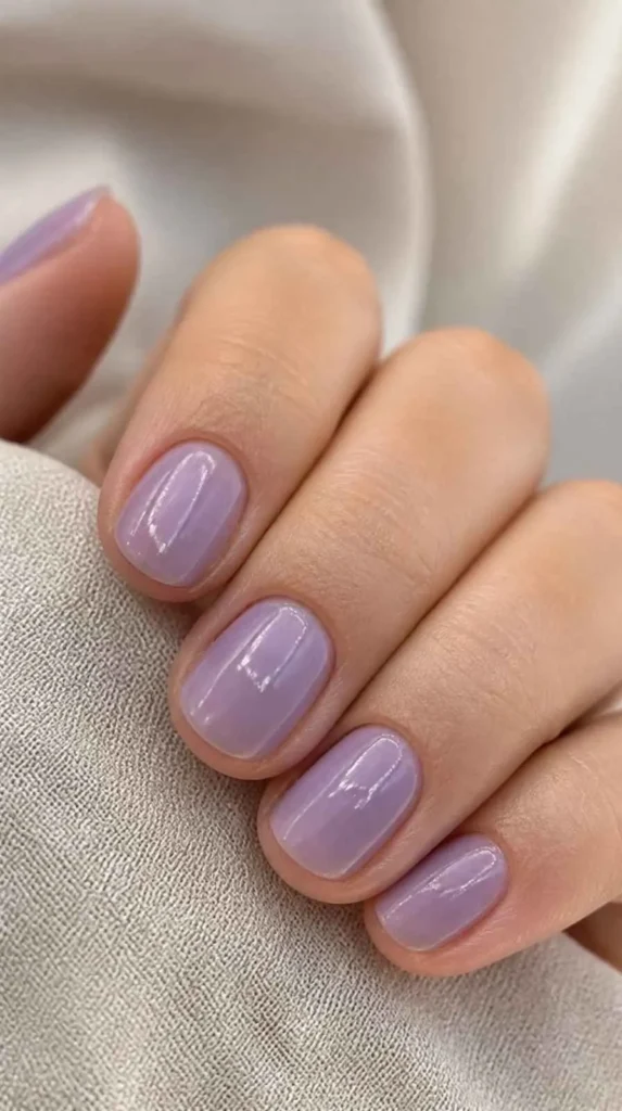 Short natural nails coated with translucent lavender jelly polish allowing natural nail texture to remain visible beneath a glossy finish.