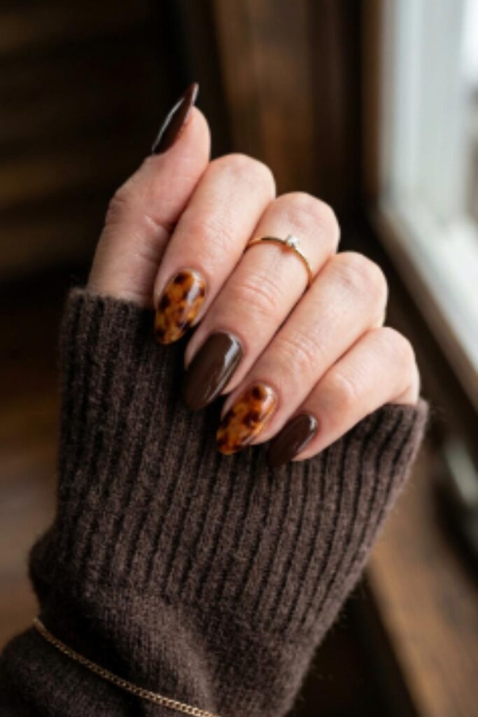 Rich chocolate brown nails with tortoiseshell accent art on two fingers creating a classy winter manicure.