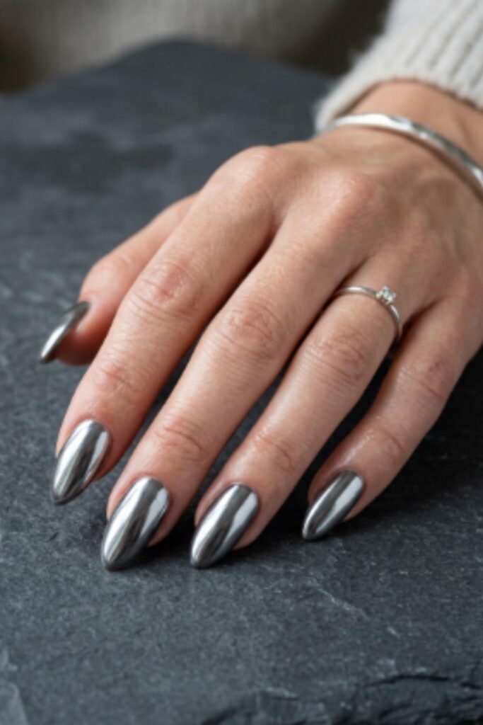 Reflective pewter grey chrome almond nails with a mirror-like metallic finish for an elegant winter manicure.