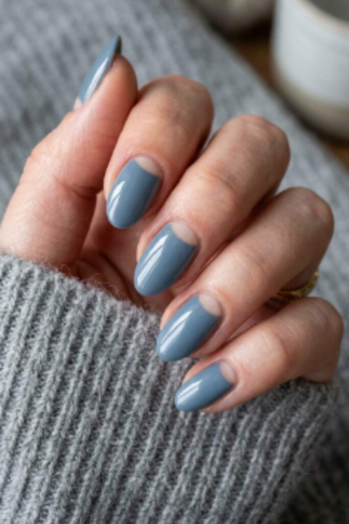 Steel blue oval nails with a nude half-moon base inspired by classic vintage manicure techniques.